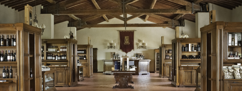 sala del castello banfi in cui vengono esposte in scaffali di legno le bottiglie di vino prodotte